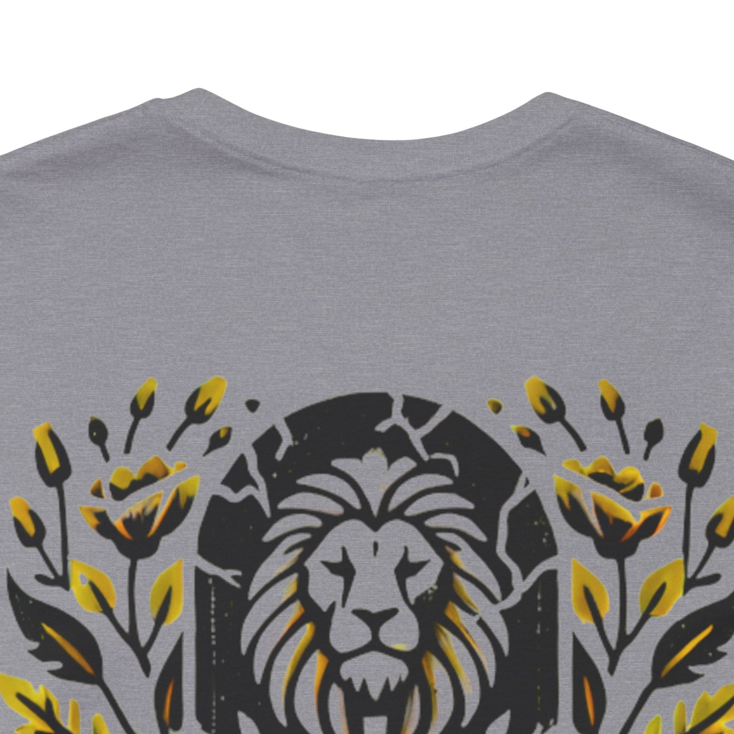 Close-up of the 'Death Defeated' T-shirt design in Heather Storm, showcasing a bold lion graphic with vibrant yellow floral details and cracked stone effects.