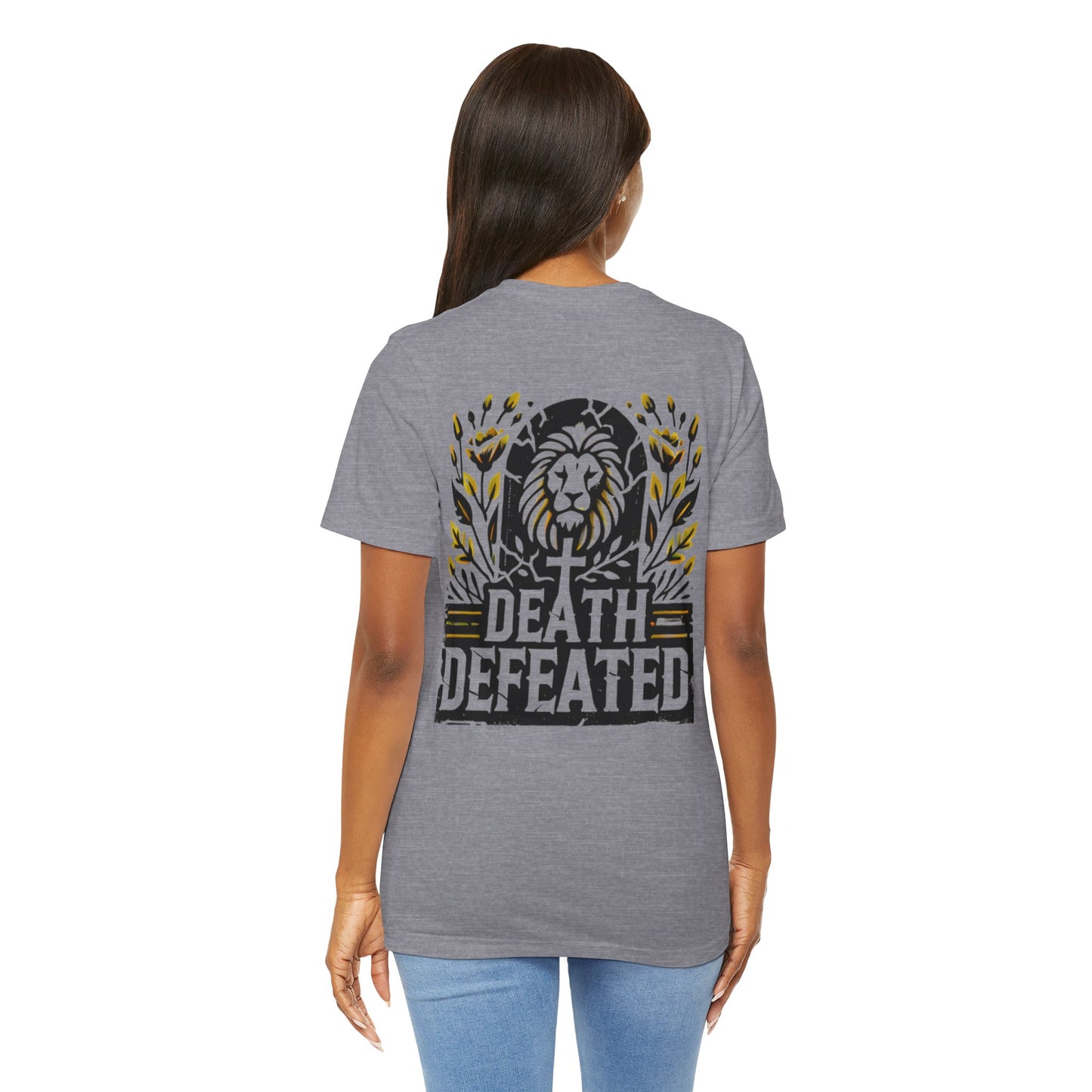 Model wearing the 'Death Defeated' T-shirt in Heather Storm, showcasing the back design with a bold lion graphic, cross, vibrant yellow floral accents, and 'Death Defeated' text.