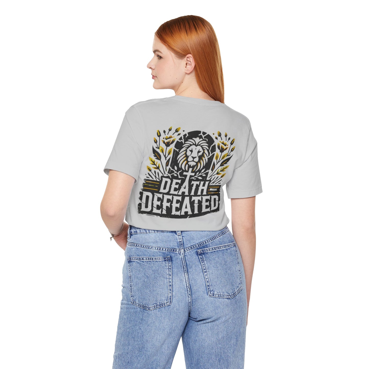 Model wearing the 'Death Defeated' T-shirt in Solid Athletic Grey, showcasing the back design with a bold lion graphic, cross, vibrant yellow floral accents, and 'Death Defeated' text.
